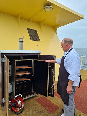 Kokken har netop lagt laksesider til rygning i skibets rygeovn (foto: Britta Gammelgaard).
